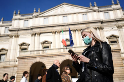 A woman wearing a face mask checks her phone outside the Teatro alla Scala, closed by authorities due to a coronavirus outbreak, in Milan, Italy February 24, 2020. Photo by Flavio Lo Scalzo/Reuters