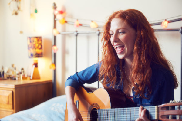 Young woman singing with guitar