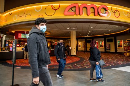 FILE PHOTO: People wear face masks as they walk by a movie theater during the coronavirus disease (COVID-19) pandemic in N...