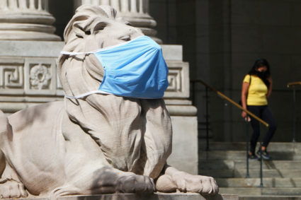 A lion statue that sits outside the New York Public Library building wears a mask