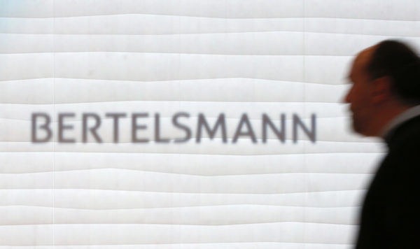 A man is silhouetted in front of the logo of German media group Bertelsmann prior to annual news conference in Berlin