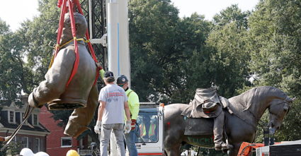 The top half of the statue of Confederate General Robert E. Lee, is moved by a crane after being cut from the rest of the ...