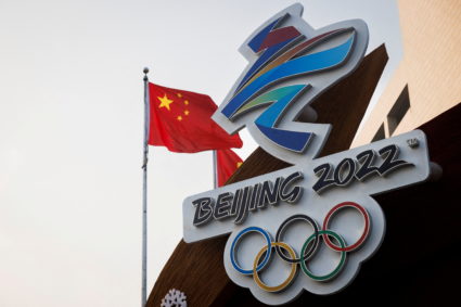 FILE PHOTO: The Chinese national flag flies behind the logo of the Beijing 2022 Winter Olympics in Beijing