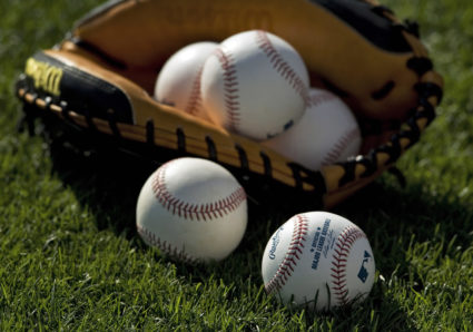 Baseballs and a catcher's mitt lie on the grass before a MLB spring training baseball game between the Red Sox and Orioles...