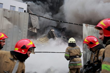Firefighters extinguish fire at a warehouse that caught flames, according to local authorities, after shelling, in the Kyi...