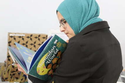 Calligraphy artist Fatima Siddiqui of checks out a children's picture book at Bushra Murad's Barakah Boutique at Michigan Ramadan Market in Westland, Michigan, in March 2022. Photo by Frances Kai-Hwa Wang/ PBS NewsHour