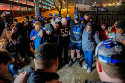 Football fans pray outside the University of Cincinnati Medical Center after Buffalo Bills defensive back Damar Hamlin col...