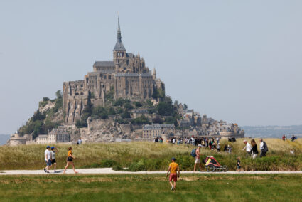 People walk past France's Mont-Saint-Michel during the French President's two-day visit in Normandy, in Le Mont-Saint-Michel