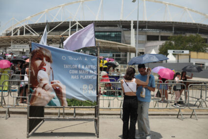 A couple protect themselves with an umbrella for high temperatures, wait before the Taylor Swift concert in Rio de Janeiro
